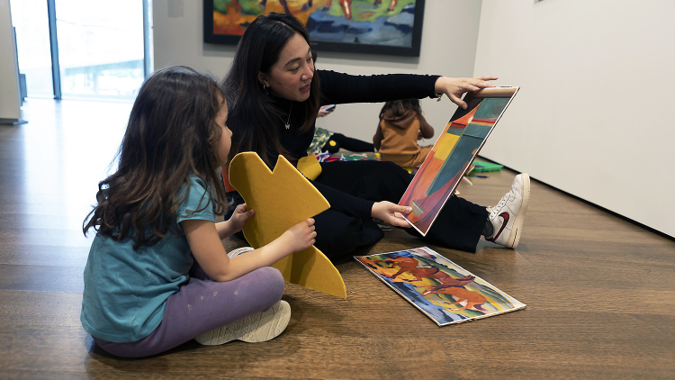 Teacher and student sitting on floor viewing art