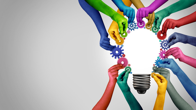 Colorful hands holding gears around a lightbulb
